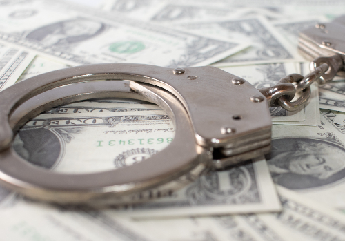 closeup-view-of-metal-handcuffs-and-dollars (1)